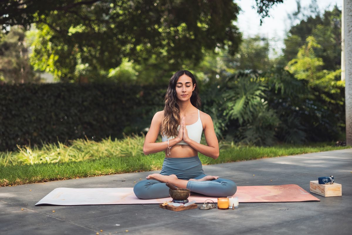 Mujer meditando al aire libre rodeada de naturaleza