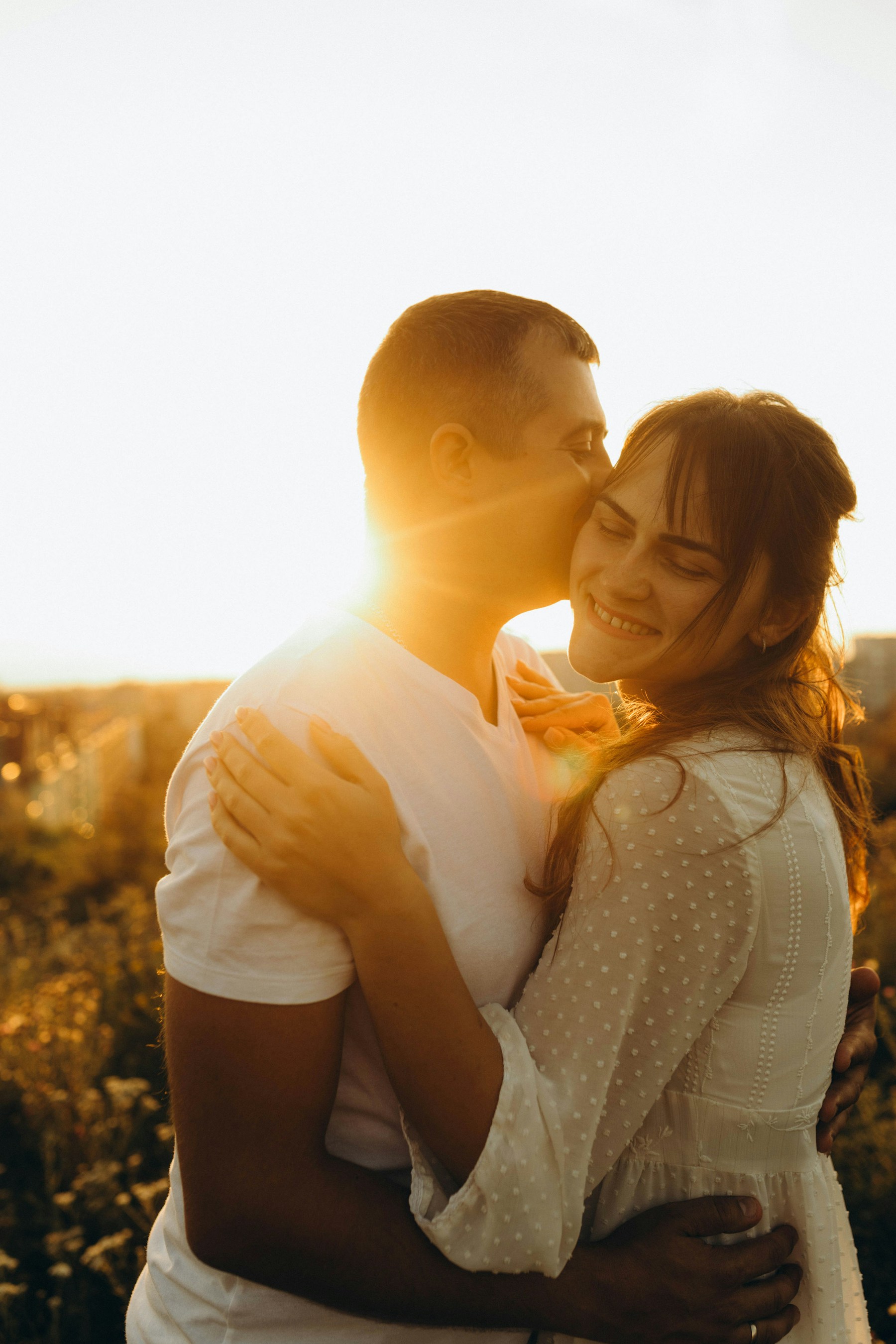 Una pareja comparte un abrazo bajo la luz cálida del sol